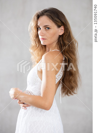 Young serious woman posing against wall background Young serious woman posing against wall background 135091740
