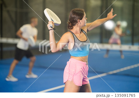 Young woman and man playing tennis against woman 135091765