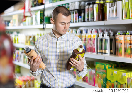 Male buyer shopping for fertilizer in hardware supermarket 135091766