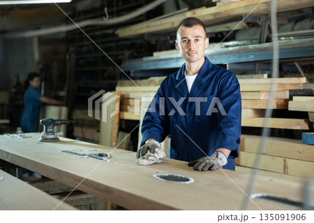 Male sawmill worker cleaning up excess resin or glue on wooden board Male sawmill worker cleaning up excess resin or glue on wooden board 135091906