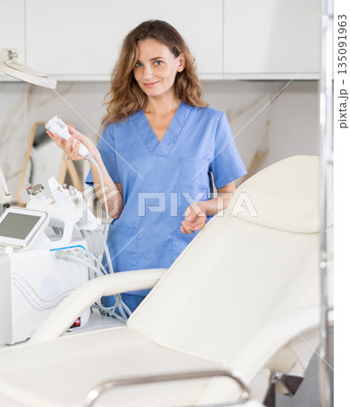 Young woman doctor posing with cosmetology apparatus Young woman doctor posing with cosmetology apparatus 135091963