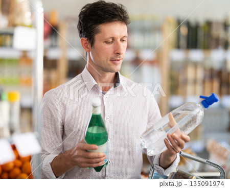 Man in light shirt choose and buy soda water in store Man in light shirt choose and buy soda water in store 135091974