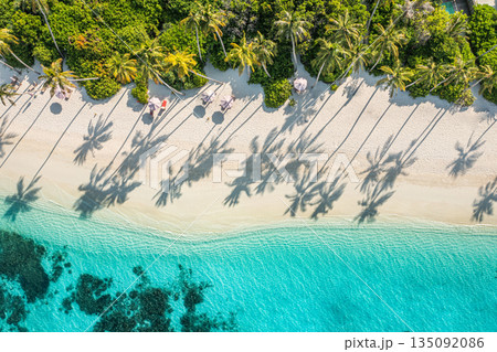 Aerial beach view, tropical island palm trees shadows on sea sand sunshine sky. Summer holiday, luxury resort, amazing landscape, top destination nature. Paradise shore, best vacation travel tourism 135092086
