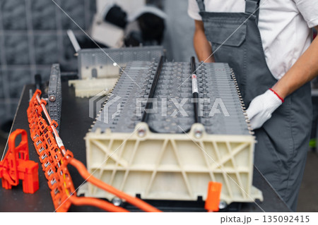Serviceman repairs electric battery pack of hybrid car 135092415
