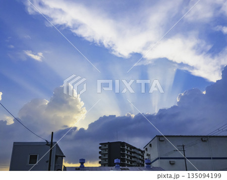 天使の梯子とドラマチックな夏の雲、空を見上げる建物 135094199