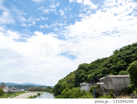 爽やかな夏の青空と雲、豊かな緑の山、川沿いの集落 135094204