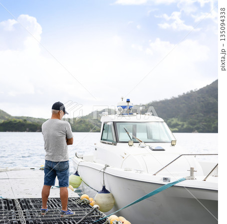 男性が桟橋で船を見る 【撮影協力：隠岐シーサイドリゾートみやび様】 135094338