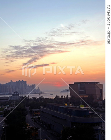 Vibrant sunset paints the sky over a modern cityscape and waterfront buildings Vibrant sunset paints the sky over a modern cityscape and waterfront buildings 135094571