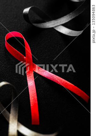 Red ribbon on a black background symbolizes World Cancer Day on February 4th. Gray ribbons surround the red ribbon, emphasizing awareness and support. 135094863