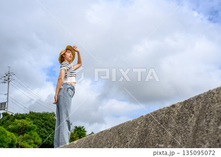 麦わら帽子で日差しを遮る女性 【撮影協力：隠岐シーサイドリゾートみやび様】 135095072