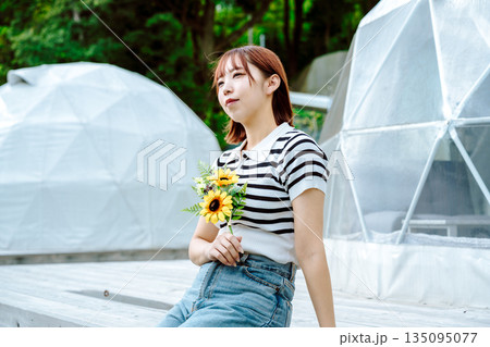 ドームテントとひまわりを持つ女性 【撮影協力：隠岐シーサイドリゾートみやび】 135095077