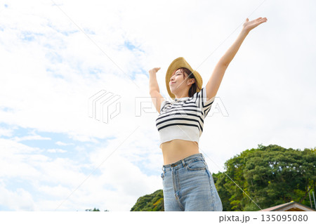 青空の下で両手を広げる女性 【撮影協力：隠岐シーサイドリゾートみやび様】 135095080