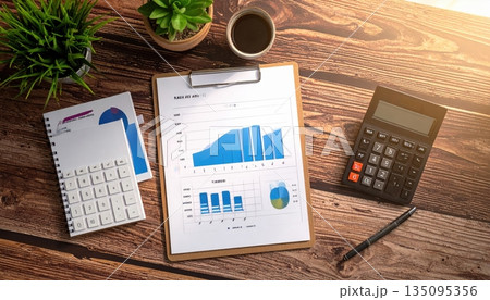 Businessman's office desk with a laptop, calculator, and financial documents showing market data and graphs 135095356