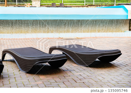 Outdoor lounge chairs near a poolside area. Outdoor lounge chairs near a poolside area. 135095746