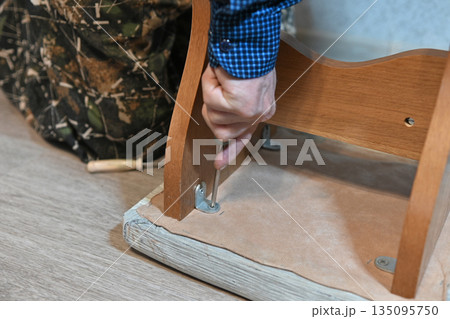 Man using power drill to assemble furniture in home setting during daytime Man using power drill to assemble furniture in home setting during daytime 135095750