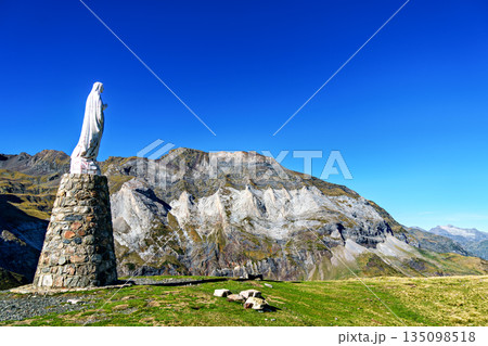Blessed virgin Mary statue at Cirque de Troumouse, Heas in France. Meadows surrounded by dramatic mountain peaks Blessed virgin Mary statue at Cirque de Troumouse, Heas in France. Meadows surrounded by dramatic mountain peaks 135098518