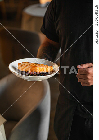 Grilled salmon fillet served by chef on plate 135099316