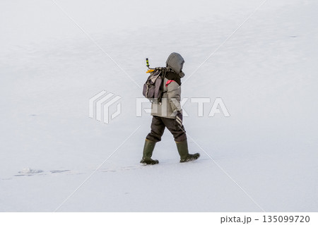 A fishman is walking through the snow 135099720