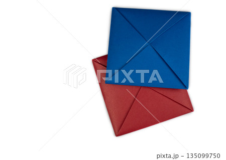 Blue and red origami sheets of paper folded into square for the game of Ddakji. Asian game of flipping colored squares. Ttakji is played on white background. Red and blue envelope Ddakji Blue and red origami sheets of paper folded into square for the game of Ddakji. Asian game of flipping colored squares. Ttakji is played on white background. Red and blue envelope Ddakji 135099750