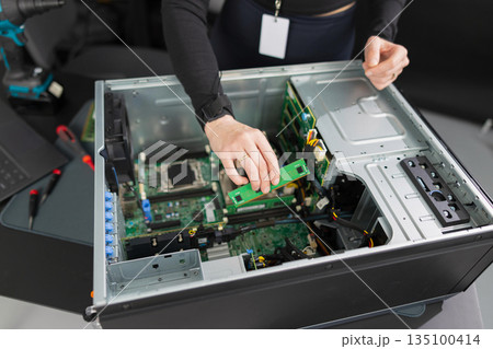 Tech worker in a server chassis upgrading RAM and components inside a desktop tower Tech worker in a server chassis upgrading RAM and components inside a desktop tower 135100414