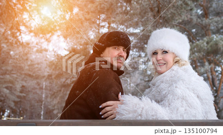 Lovers Nestled On Nature Bench, Romantic Duo Sitting Closely Amid Winter Woods Under Sunlight, Two Individuals Expressing Warmth And Affection On Rustic Bench With Snowy Pine Trees Around Lovers Nestled On Nature Bench, Romantic Duo Sitting Closely Amid Winter Woods Under Sunlight, Two Individuals Expressing Warmth And Affection On Rustic Bench With Snowy Pine Trees Around 135100794