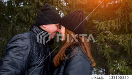 Intimate Moment Beneath Trees, Closeup Of Lovers In Wintry Forest Scene Conveying Warmth And Affection, An Affectionate Couple Resting Their Foreheads Together Beneath Fir Branches In Chilly Air 135100820