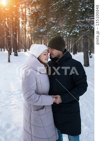 Lovers Sharing Warm Feelings Amidst Snowy Woods, An Affectionate Pair Exchanging Heat Beneath Icy Woodland Canopy, Two Individuals Found Comfort Together Within Cold And Snowy Forest Landscape 135100848