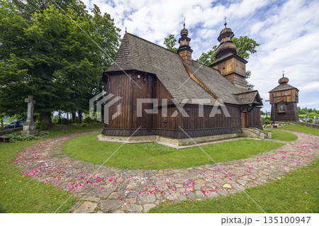 Traditional wooden church with bell tower and stone path covered in flower petals 135100947