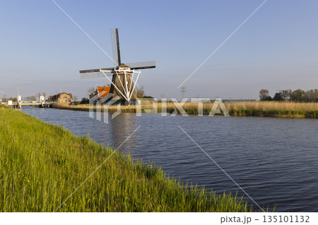 Dutch windmill by canal in Heerhugowaard, Netherlands Dutch windmill by canal in Heerhugowaard, Netherlands 135101132