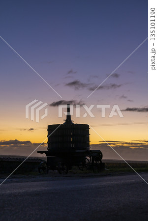 Traditional wine press silhouette against sunset sky in Vougeot 135101190