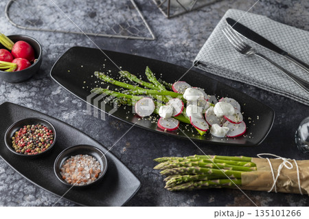 Asparagus radish mozzarella salad serving on black plate 135101266