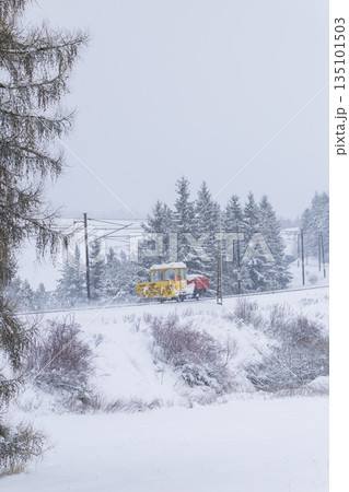 Yellow snowplow clearing tracks in Strba, Slovakia winter 135101503