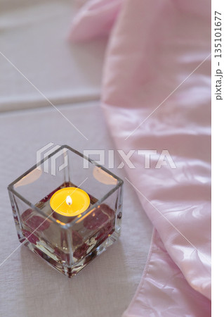 Tealight candle glowing in glass holder with pink fabric Tealight candle glowing in glass holder with pink fabric 135101677