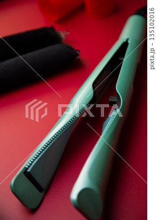 In the foreground is a curling iron loi creating curls against the background of curlers in outfocus on a pink background. The concept of hair care, hairstyle, hairdressing. High quality photo 135102016