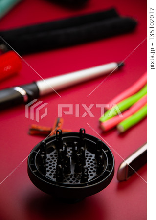 In the foreground is a diffuser for creating curls and hair volume against the background of curlers and irons in out-of-focus on a pink background. The concept of hair care, hairstyle, hairdressing 135102017
