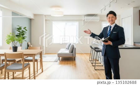 リノベーション済みの明るいリビングで室内を案内する不動産営業マン 135102688
