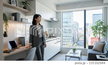都心の高層マンションで窓の外を眺めるキャリアウーマンの女性 135102944