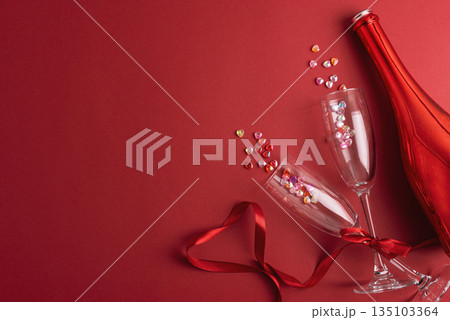 Champagne Bottle and Flute Glasses with Colorful Hearts on Red Background. Valentines Day Celebration 135103364