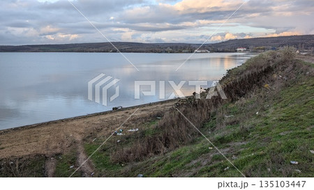 Idyllic lakeside view with rolling hills and smooth reflection Idyllic lakeside view with rolling hills and smooth reflection 135103447