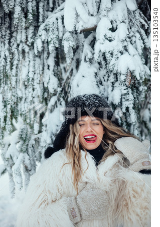 Woman smiling in snow-covered landscape near pine trees on a winter day Woman smiling in snow-covered landscape near pine trees on a winter day 135103540