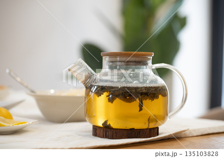 Glass teapot brewing herbal tea on wooden table 135103828