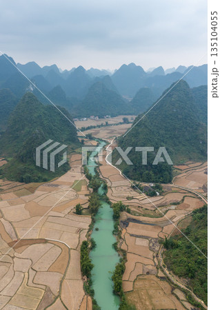 Turquoise river flowing through cultivated fields in valley between karst mountains in Ha Giang, Vietnam Turquoise river flowing through cultivated fields in valley between karst mountains in Ha Giang, Vietnam 135104055