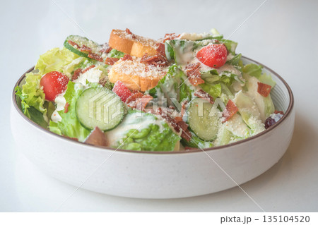 Caesar Salad: Crisp romaine lettuce tossed with Parmesan, croutons, and a creamy Caesar dressing, 135104520