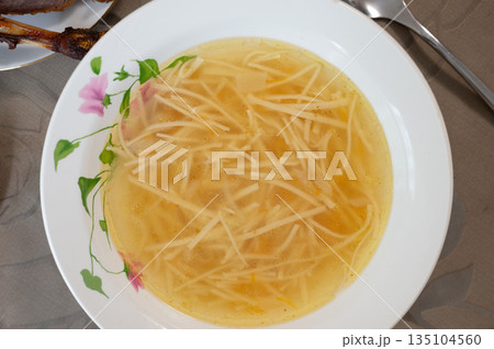 Chicken soup with noodles served on a white plate Chicken soup with noodles served on a white plate 135104560