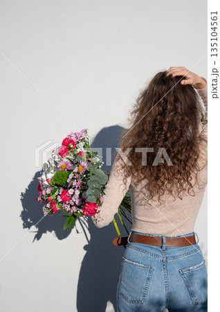 Woman Holding Vibrant Bouquet Against White Wall 135104561