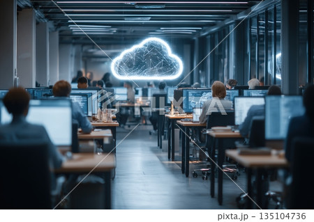 Employees work in a modern office focusing on cloud computing and data analysis with multiple laptops in use 135104736