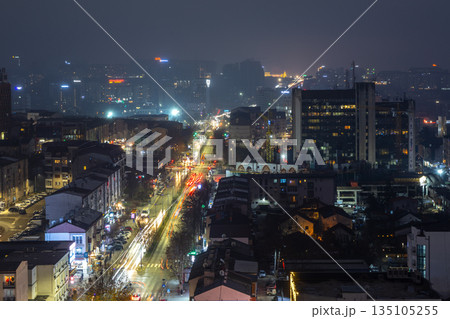 Modern cityscape of Pristina in Kosovo at night with illuminated skyline, residential districts, office towers and long exposure highlighted traffic trails 135105255