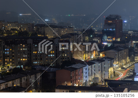 Night panorama of Pristina, capital city center of Kosovo, with residential architecture, apartment buildings, warm window lights and winter urban mood 135105256
