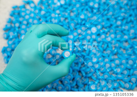 Female hand holding laboratory syringe filters, concept of sterile sample preparation. 135105336