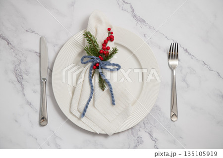 Christmas table setting with white plate, napkin, fir tree branch and red berries decoration Christmas table setting with white plate, napkin, fir tree branch and red berries decoration 135105919